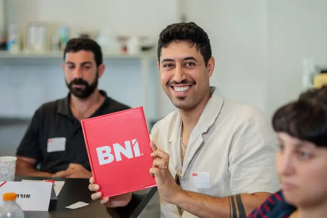 חבר קבוצה מציג ערכת BNI ומחייך למצלמה